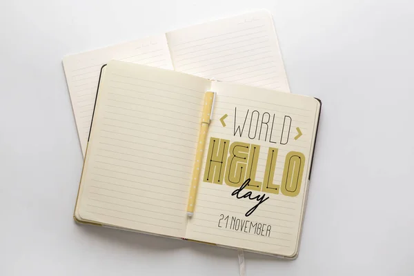 Notebooks with text WORLD HELLO DAY on light background