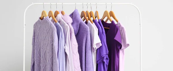 Hanger with clothes in purple shades on light background