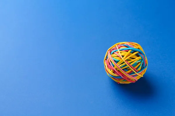Colorful rubber band ball on blue background
