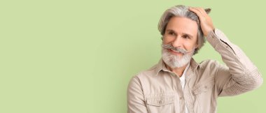 Stylish bearded senior man on green background with space for text