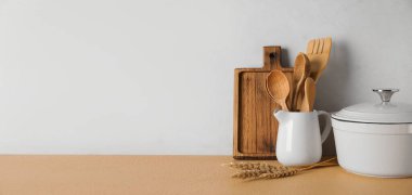 Set of kitchen utensils on table against light background with space for text