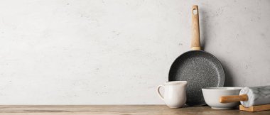 Set of kitchen utensils on table against light background with space for text