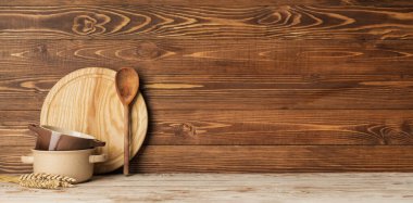 Set of kitchen utensils on table against wooden background with space for text
