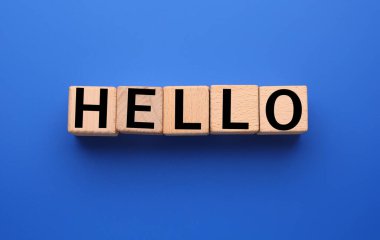 Word HELLO made of cubes on blue background, top view