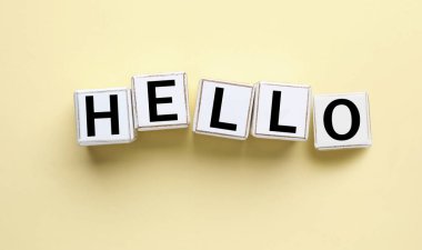 Word HELLO made of cubes on yellow background, top view