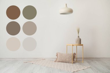 Oturma odasındaki ışık duvarının yanında vazo ve yastıklı masa. Farklı renk desenleri