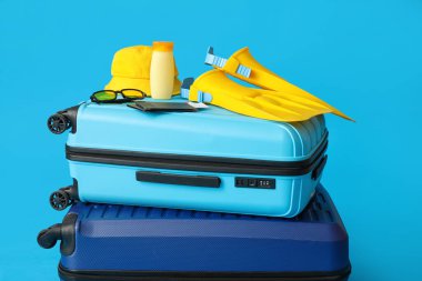 Suitcases with beach accessories, passports and tickets on blue background