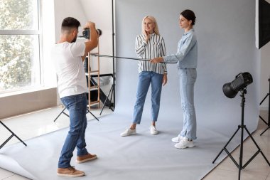 Male photographer and his assistant working with mature woman in studio