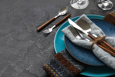 Trendy dinnerware with napkin and cutlery in plate on black table