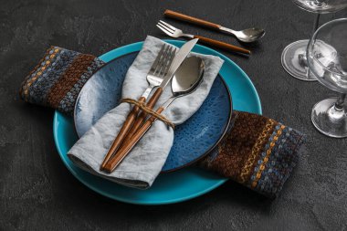 Trendy dinnerware with napkin and cutlery in plate on black table