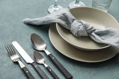 Simple dinnerware with plates, cutlery and napkin on color table