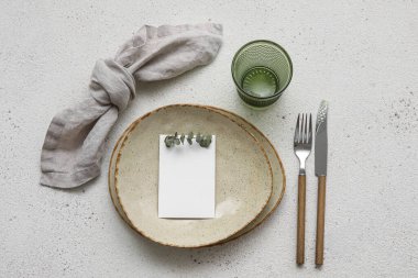 Blank card and eucalyptus branch in plate on light background