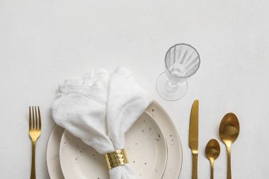 Table setting with stylish cutlery, glass and napkin in plate on white background