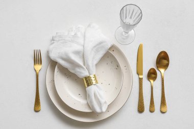 Table setting with stylish cutlery, glass and napkin in plate on white background