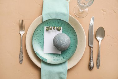 Table setting with blank card, candle and eucalyptus branch on beige background
