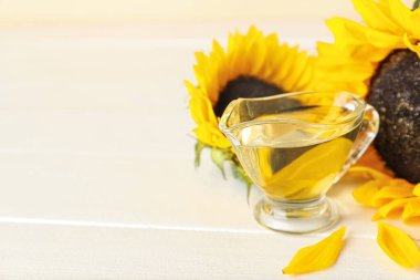 Gravy boat of sunflower oil on light wooden table
