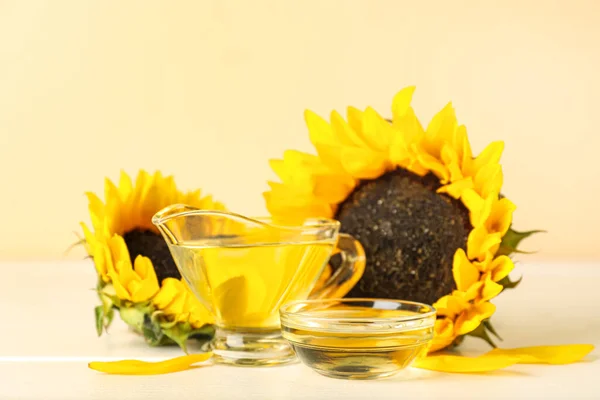 Gravy boat and bowl of sunflower oil on table against color background