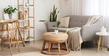 Interior of light living room with comfortable sofa, pouf and table