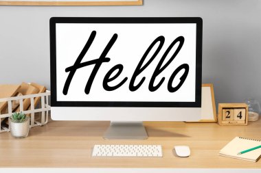 Modern computer with word HELLO on screen in room 