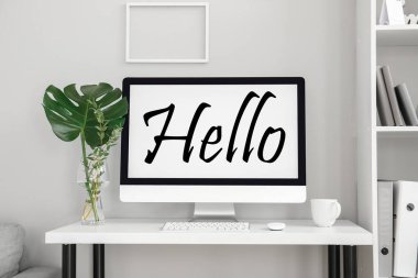 Modern computer with word HELLO on screen at workplace