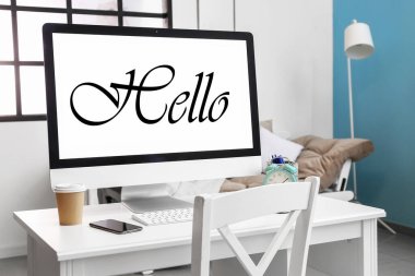 Modern computer with word HELLO on screen in room 