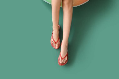 Legs of young woman with inflatable ring on green background