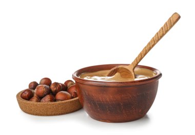 Bowls of tasty hazelnut butter and nuts isolated on white background