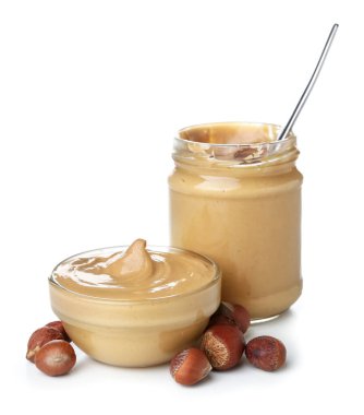Bowl and jar of tasty hazelnut butter on white background