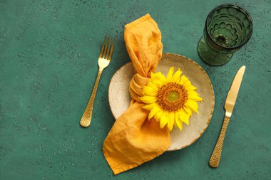 Table setting with sunflower on green background