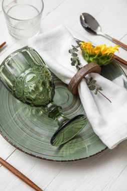 Dinnerware and sunflower on white wooden table, closeup
