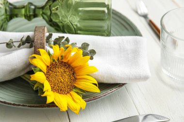 Dinnerware and sunflower on white wooden table, closeup