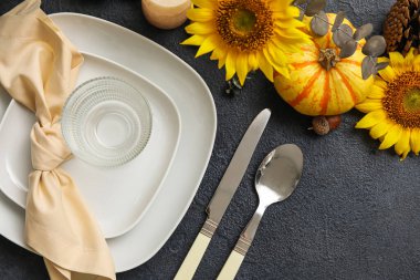 Beautiful table setting with autumn decor and sunflowers on dark background