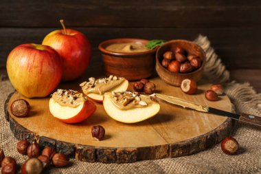 Board of tasty apple wedges with nut butter on wooden table, closeup