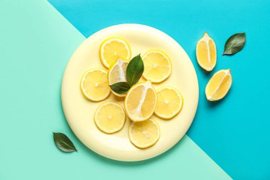 Plate with slices of ripe lemon on color background