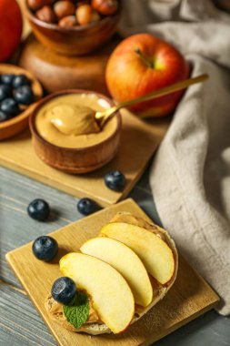 Tasty sandwich with nut butter and apples on grey wooden table, closeup