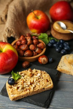 Tasty sandwich with nut butter and walnuts on dark wooden table, closeup