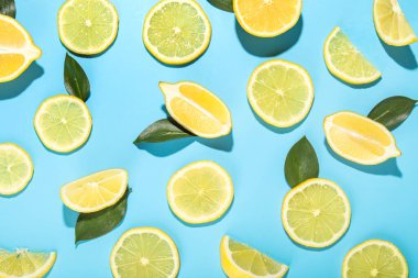 Slices of fresh lemons and leaves on color  background