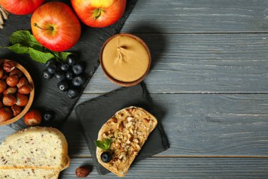 Tasty sandwich with nut butter, hazelnuts and blueberry on dark wooden background