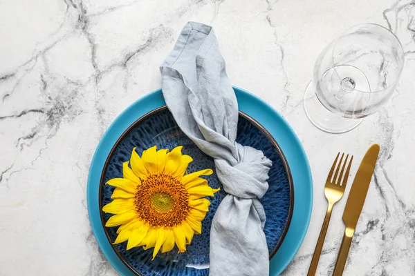 Stylish table setting with sunflower on white marble background