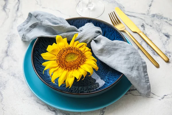 Stylish dinnerware and sunflower on white marble table