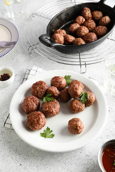 Baking dish with tasty meat balls, plates and sauce on grunge background