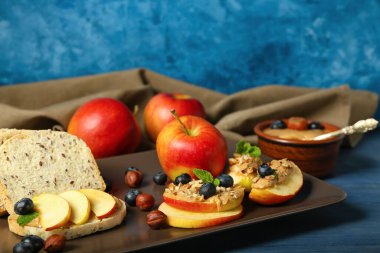 Plate of fresh apples with nut butter and blueberry on table, closeup