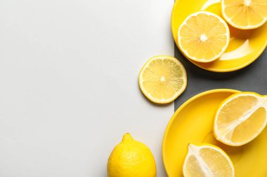 Plates with ripe lemons on light background