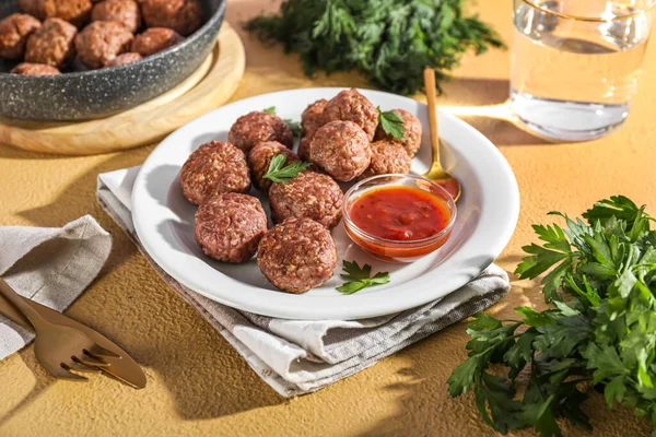 Plate with tasty meat balls, parsley, sauce, spoon and napkin on beige background