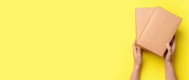 Hands and paper boxes on yellow background with space for text, top view
