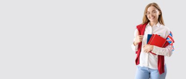 Young female student with UK flag and books on light background with space for text