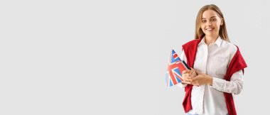 Young female student with UK flag and books on light background with space for text