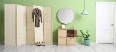 Interior of stylish hallway with folding screen and mirror 