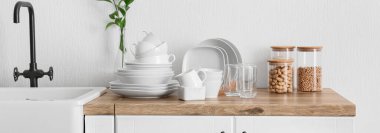 Interior of stylish kitchen with dinnerware, products and sink on counter