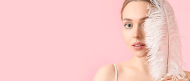 Beautiful young woman with soft feather on pink background with space for text